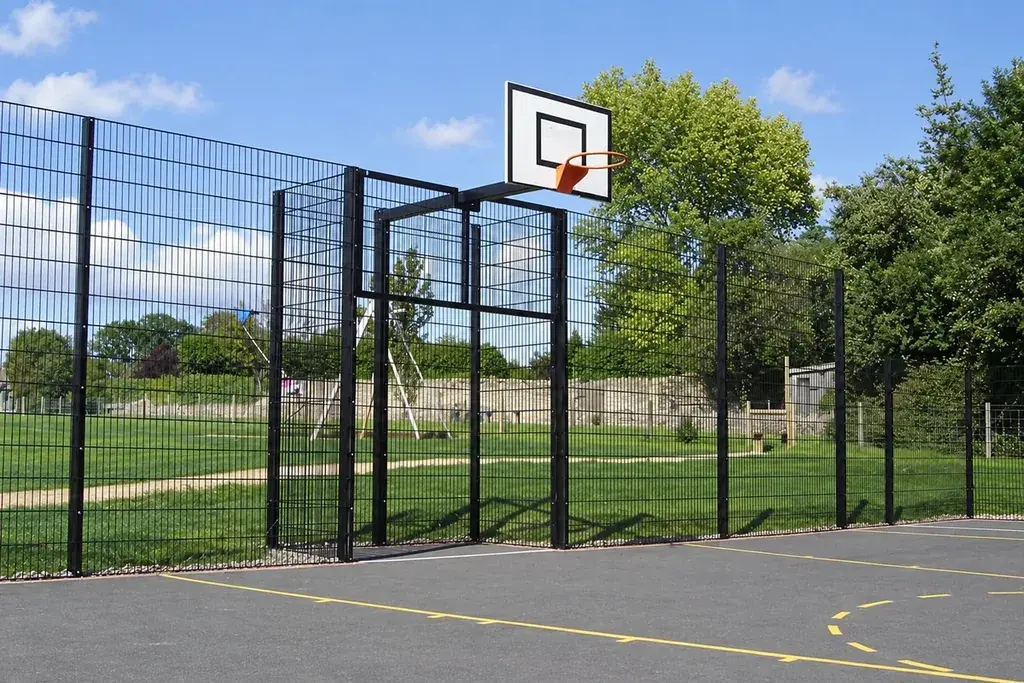 Sports court mesh enclosure with basketball hoop and support posts