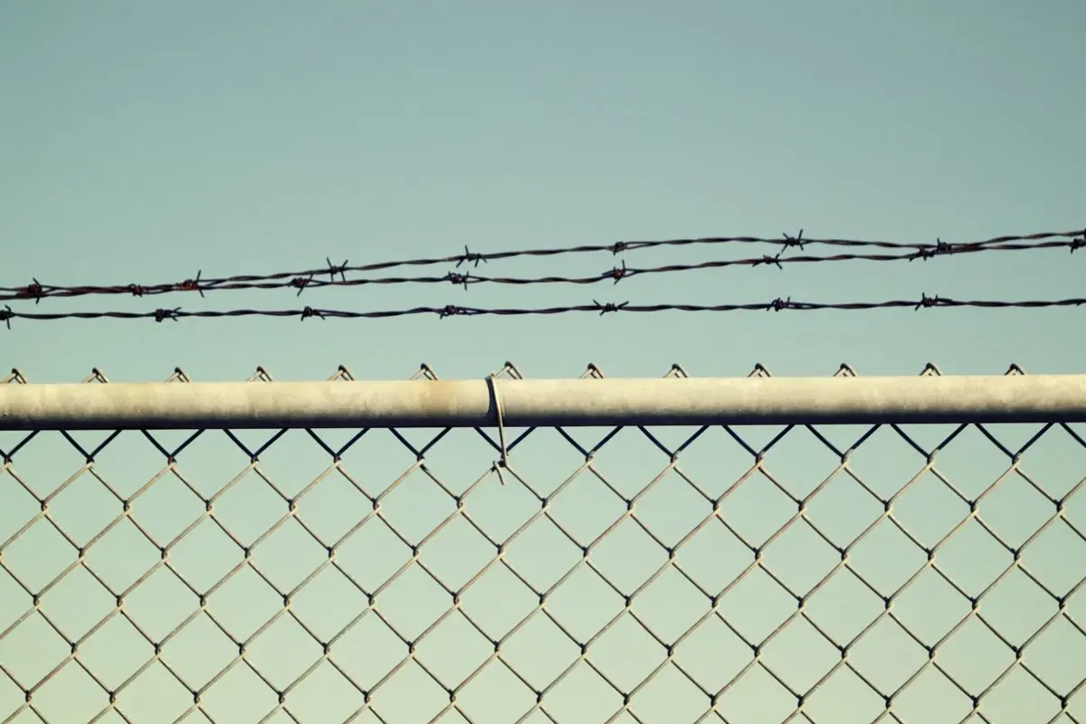 Barbed wire strands mounted above a chain-link fence