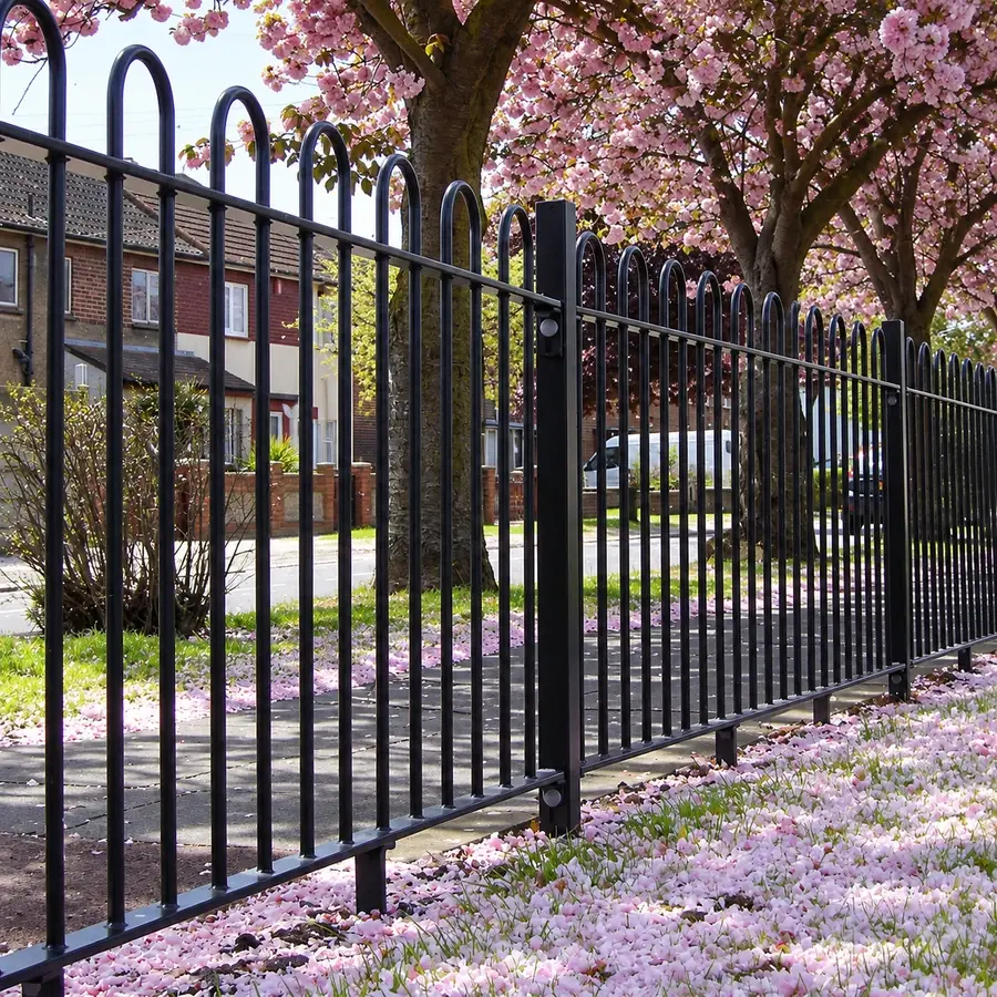 Black bow top railings along a paved urban boundary
