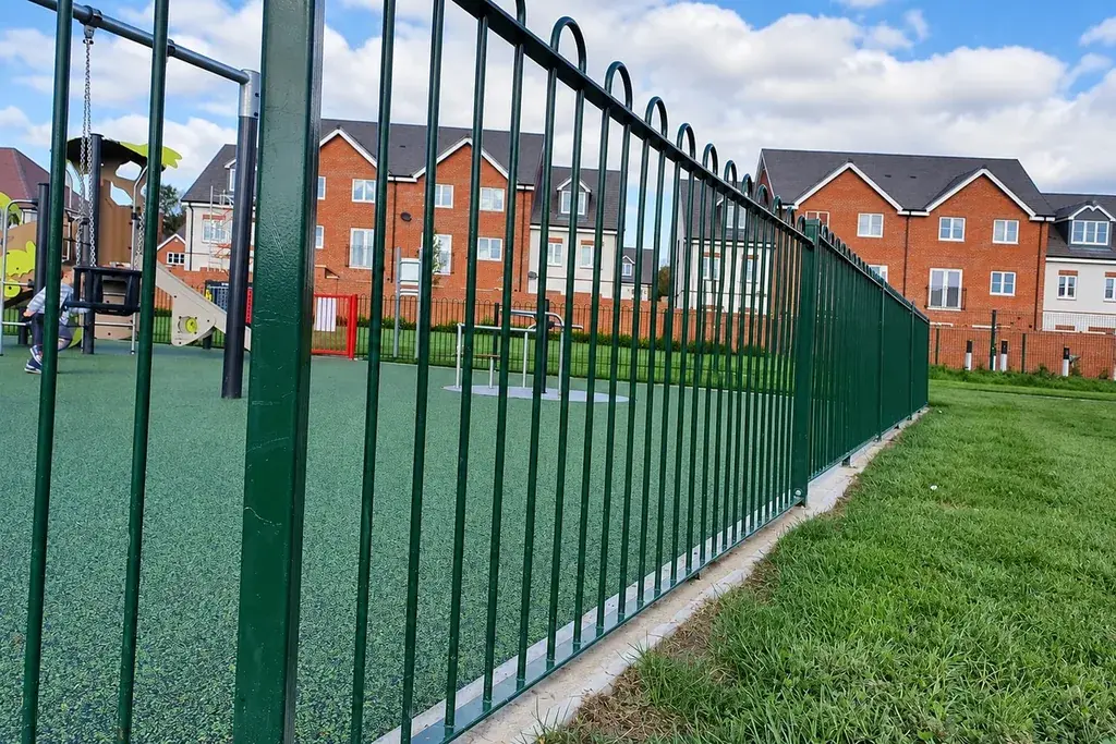 Green bow top railing run beside a sloping grass verge