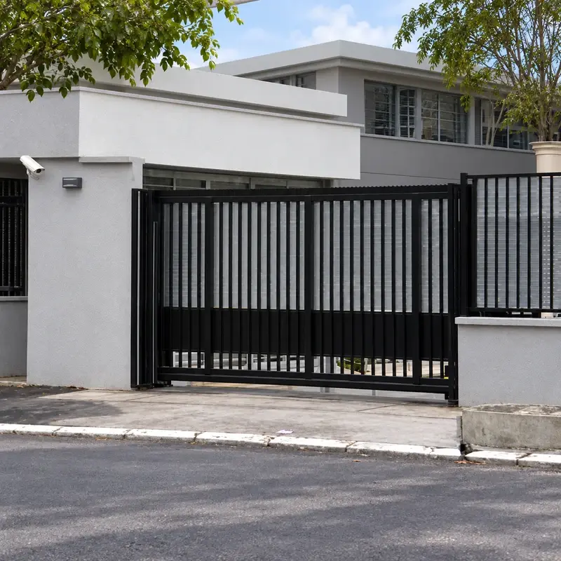 Dark vertical-bar cantilever sliding gate at a building entrance