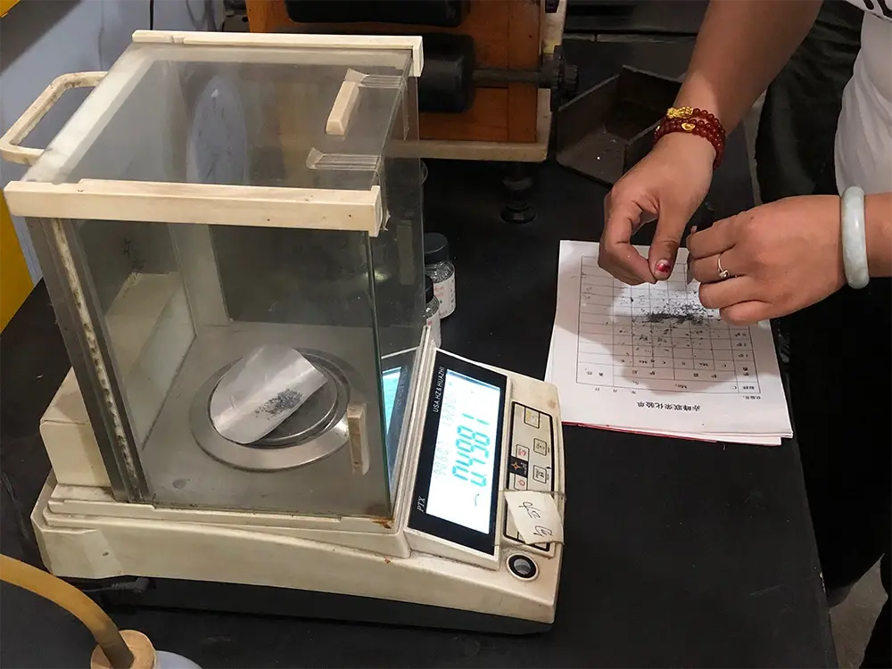 Material sample on a laboratory balance beside a handwritten inspection sheet