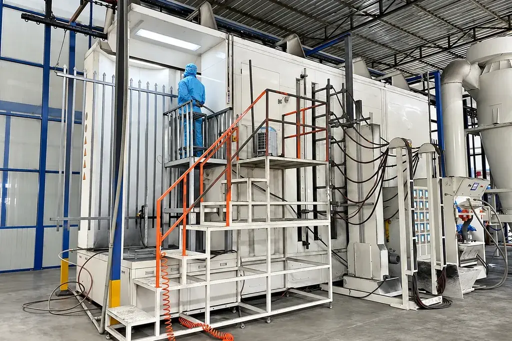 Worker beside a suspended fence section at a powder coating booth