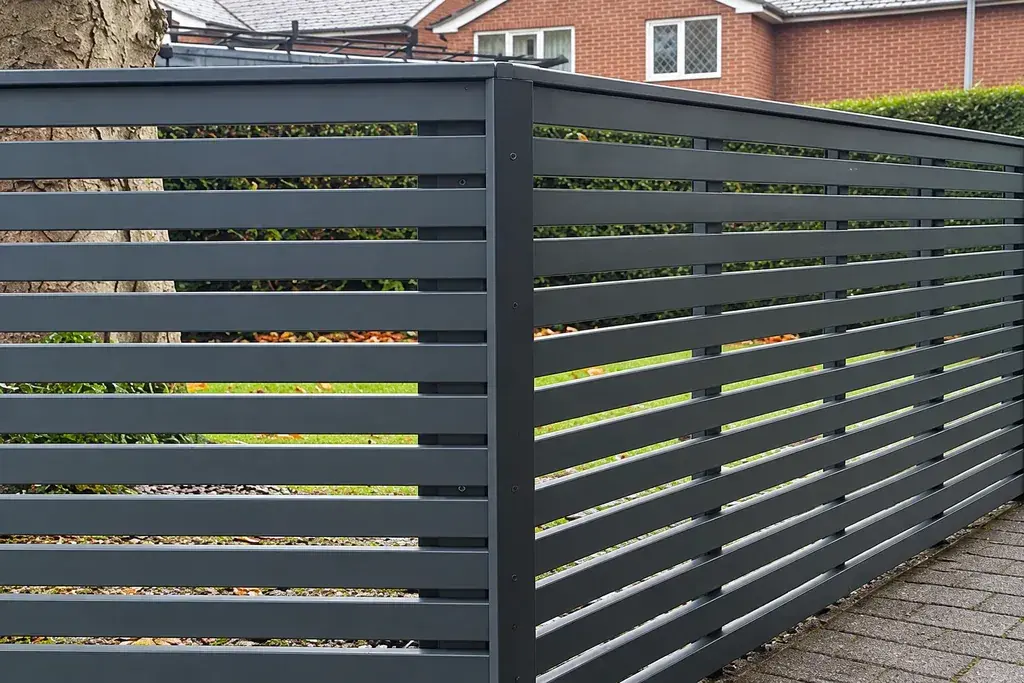 Dark horizontal slat fence forming a corner beside paving