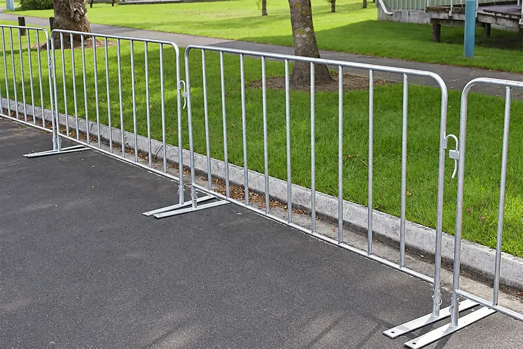 Galvanised crowd-control barriers with flat feet beside a lawn