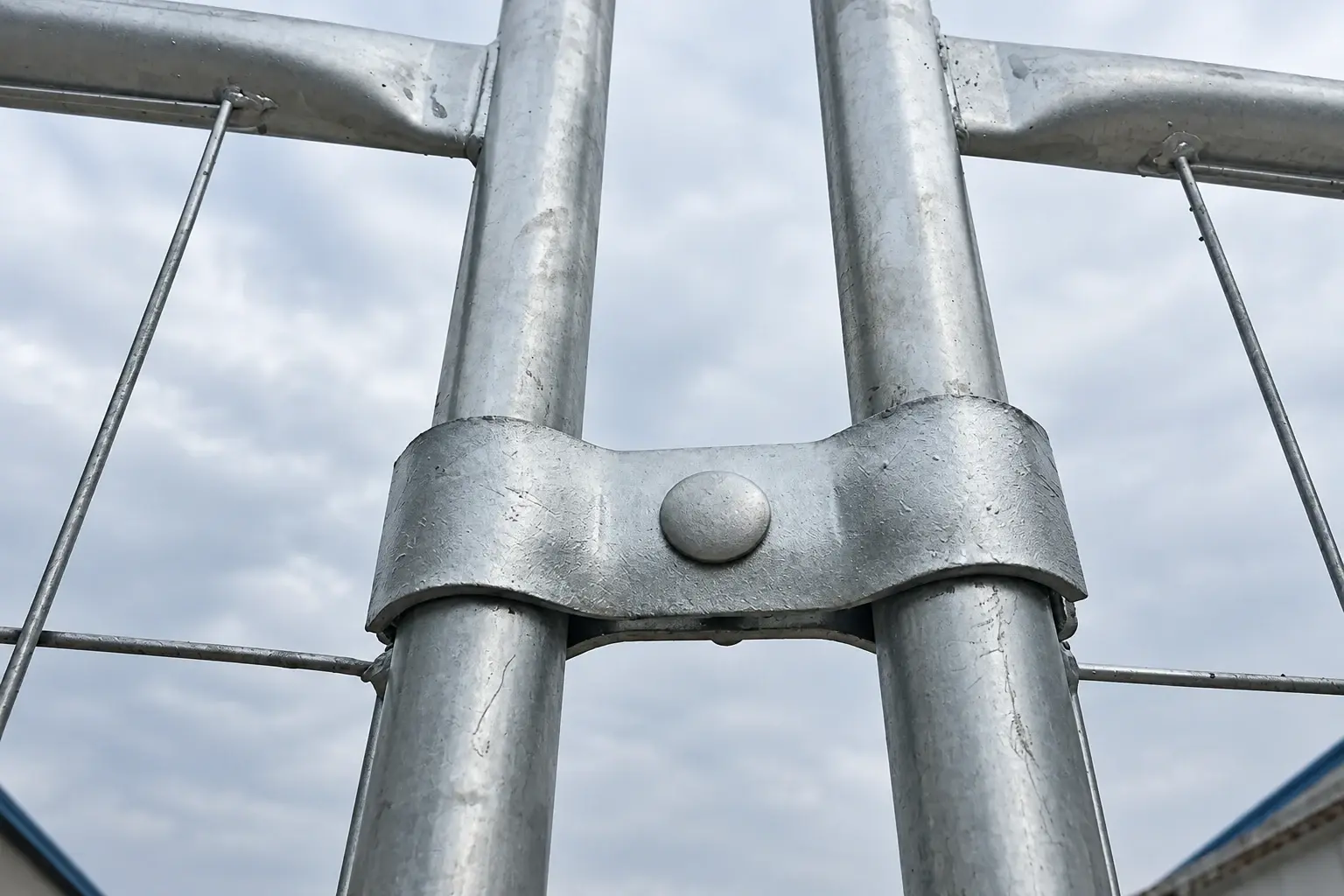 Galvanised clamp joining two round temporary-fence uprights