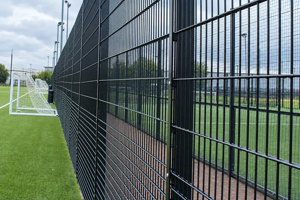 Black welded mesh sports fence beside an artificial-turf pitch
