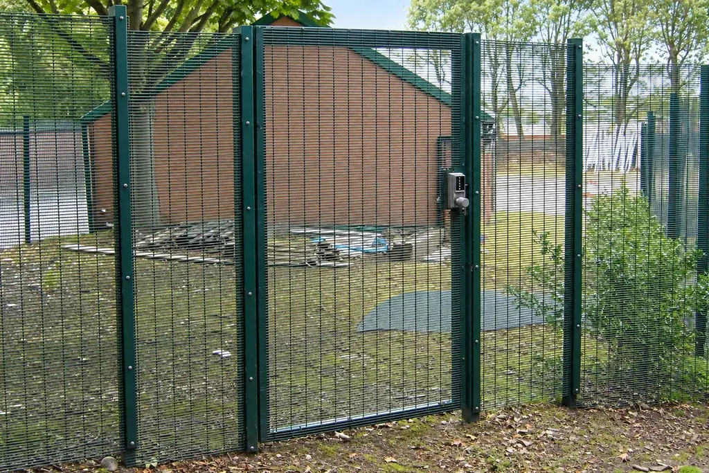 Mesh pedestrian gate with access control beside a fenced service area
