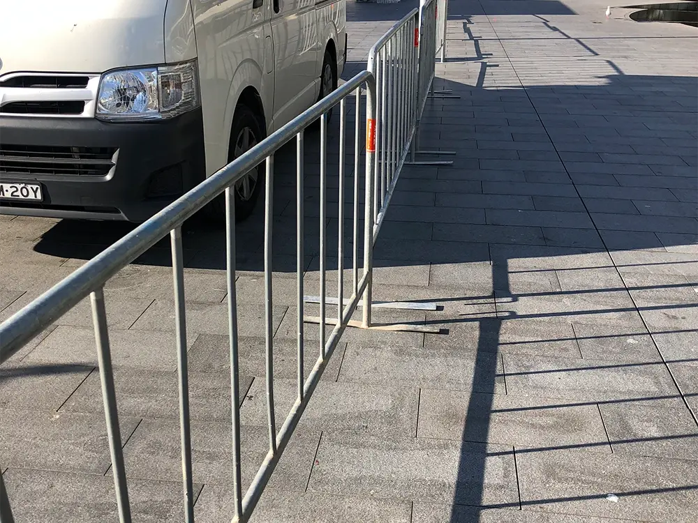 Crowd barrier feet projecting onto a paved pedestrian surface