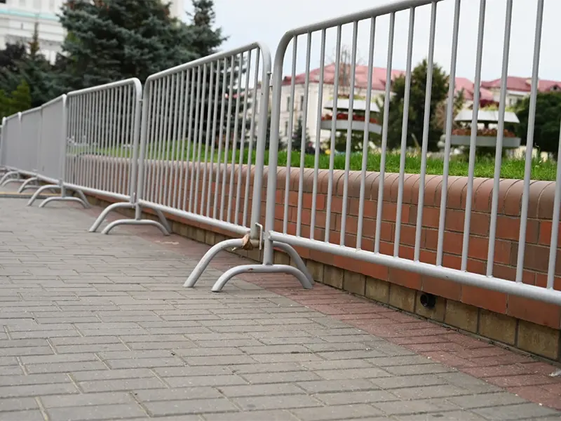 Linked galvanised crowd barriers alongside a paved pedestrian route