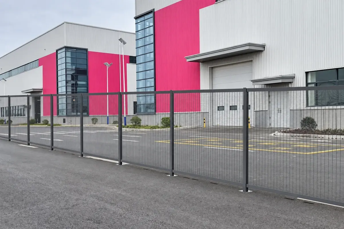 Metal mesh fence panels and posts outside an industrial building.