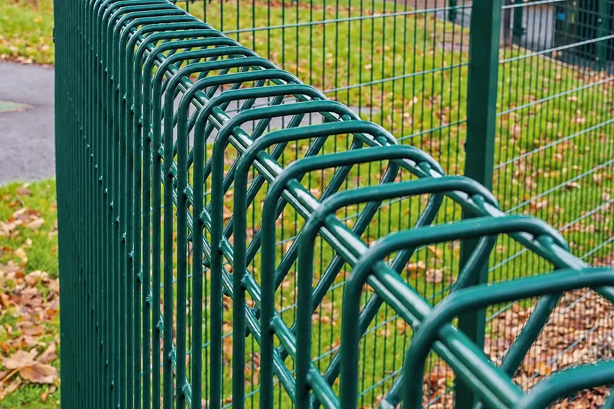Close view along the top edge of green rigid welded mesh fence panels