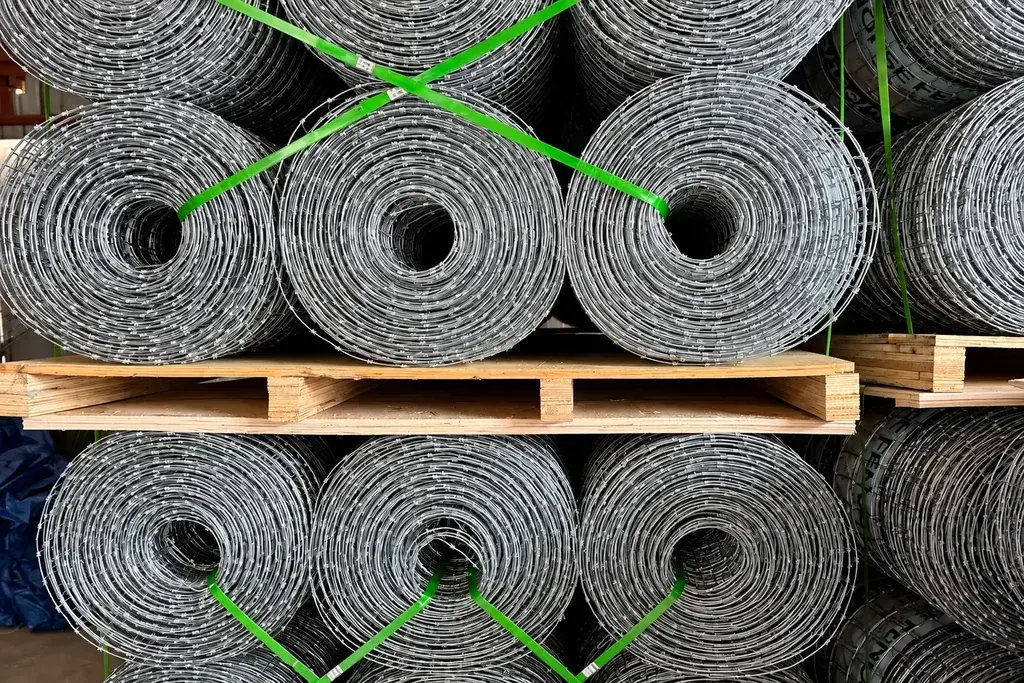 Galvanised wire fence rolls bundled in layers on wooden pallets