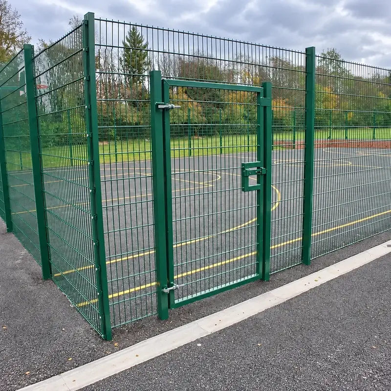 Green twin-wire pedestrian gate beside a paved path