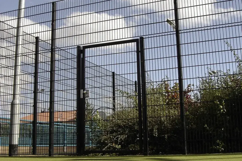 Black twin-wire gate with hinges and latch at fence posts