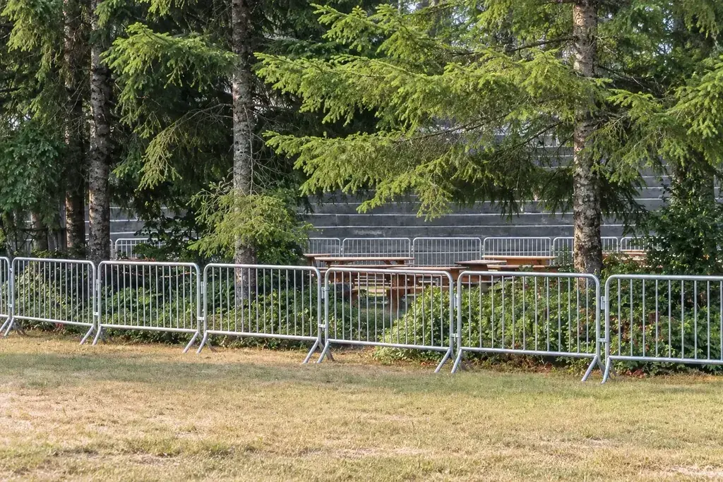 Mobile metal pedestrian barriers along a tree-lined public route