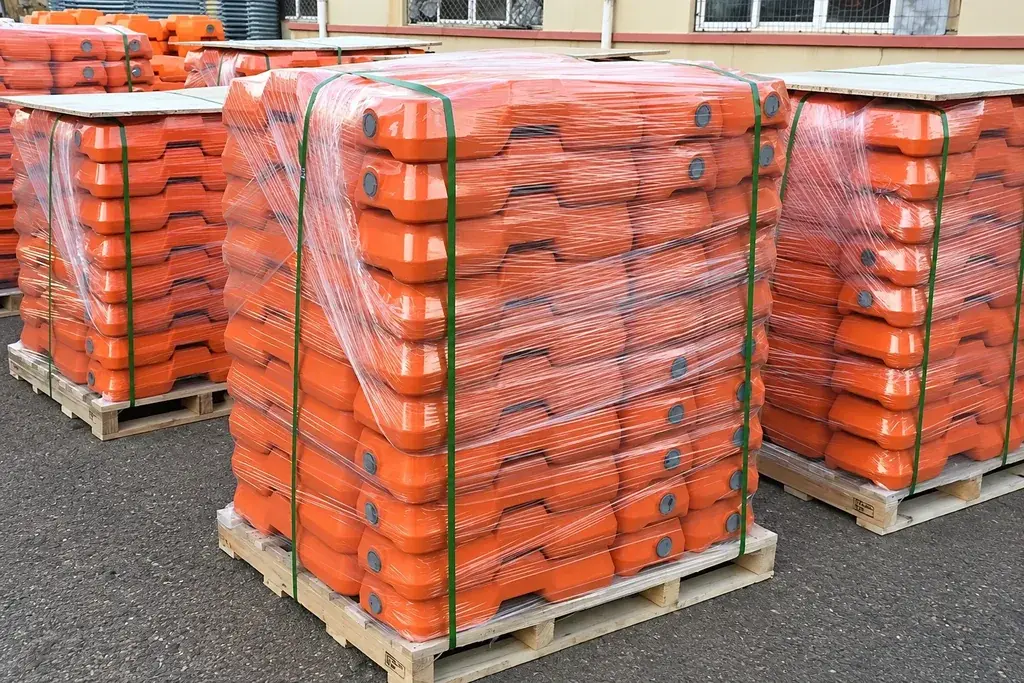Pallets of orange temporary fence feet wrapped for transport