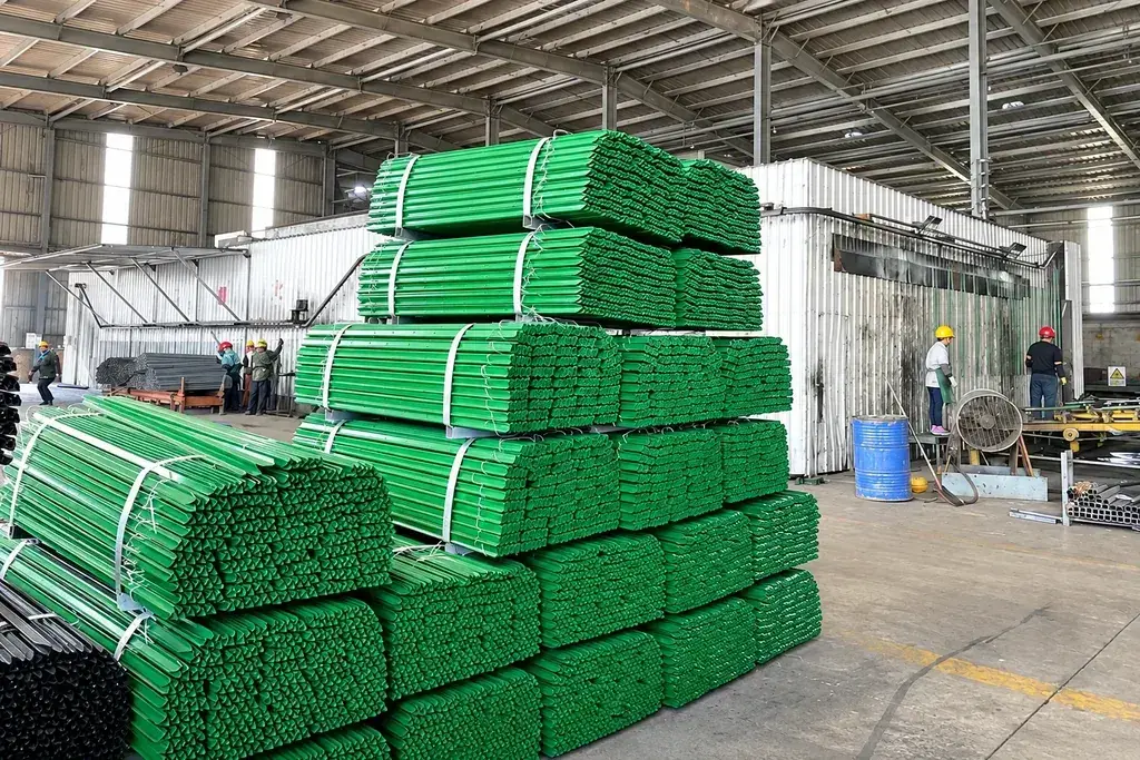 Green coated steel fence pales bundled and stacked inside a workshop