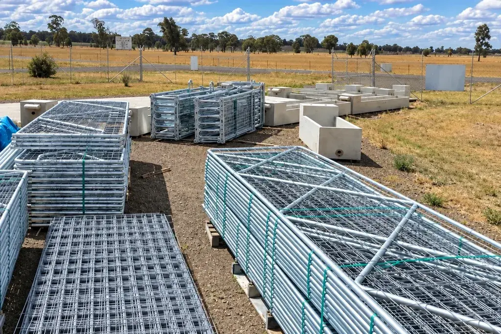 Stacks of galvanised mesh farm gates in an outdoor storage yard