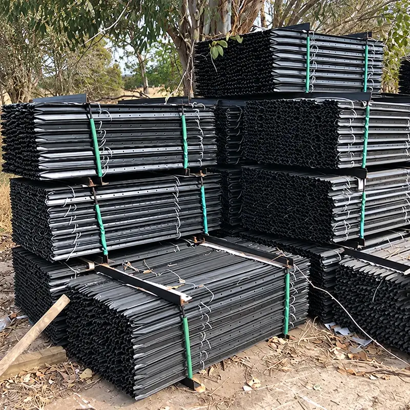 Black steel Y-posts stacked in bundles at a storage yard