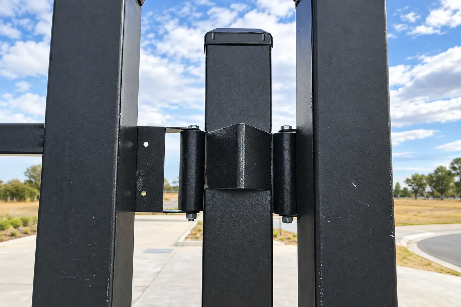 Black gate post with bolted receiver brackets beside two gate frames