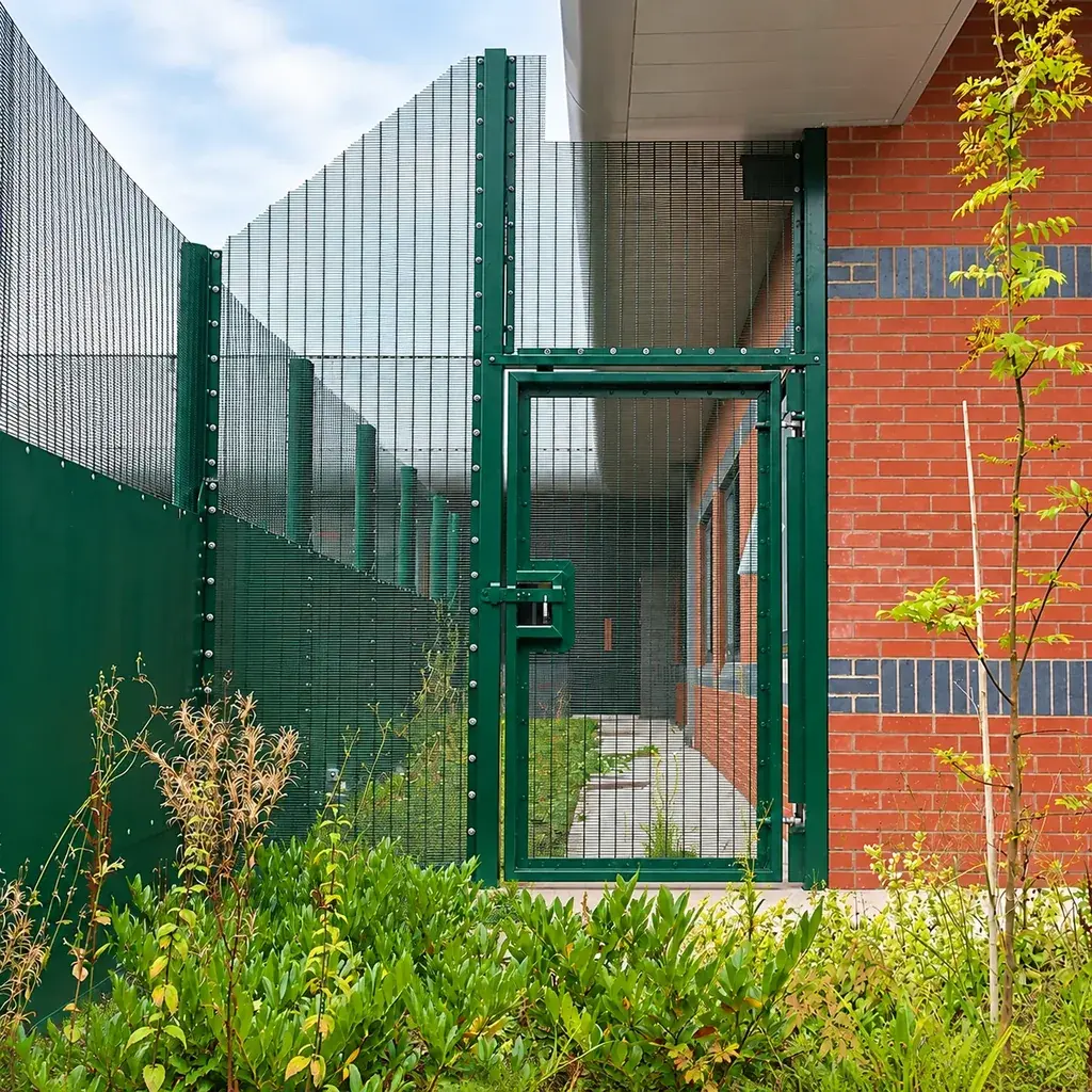 Green 358 mesh pedestrian gate beside a brick building