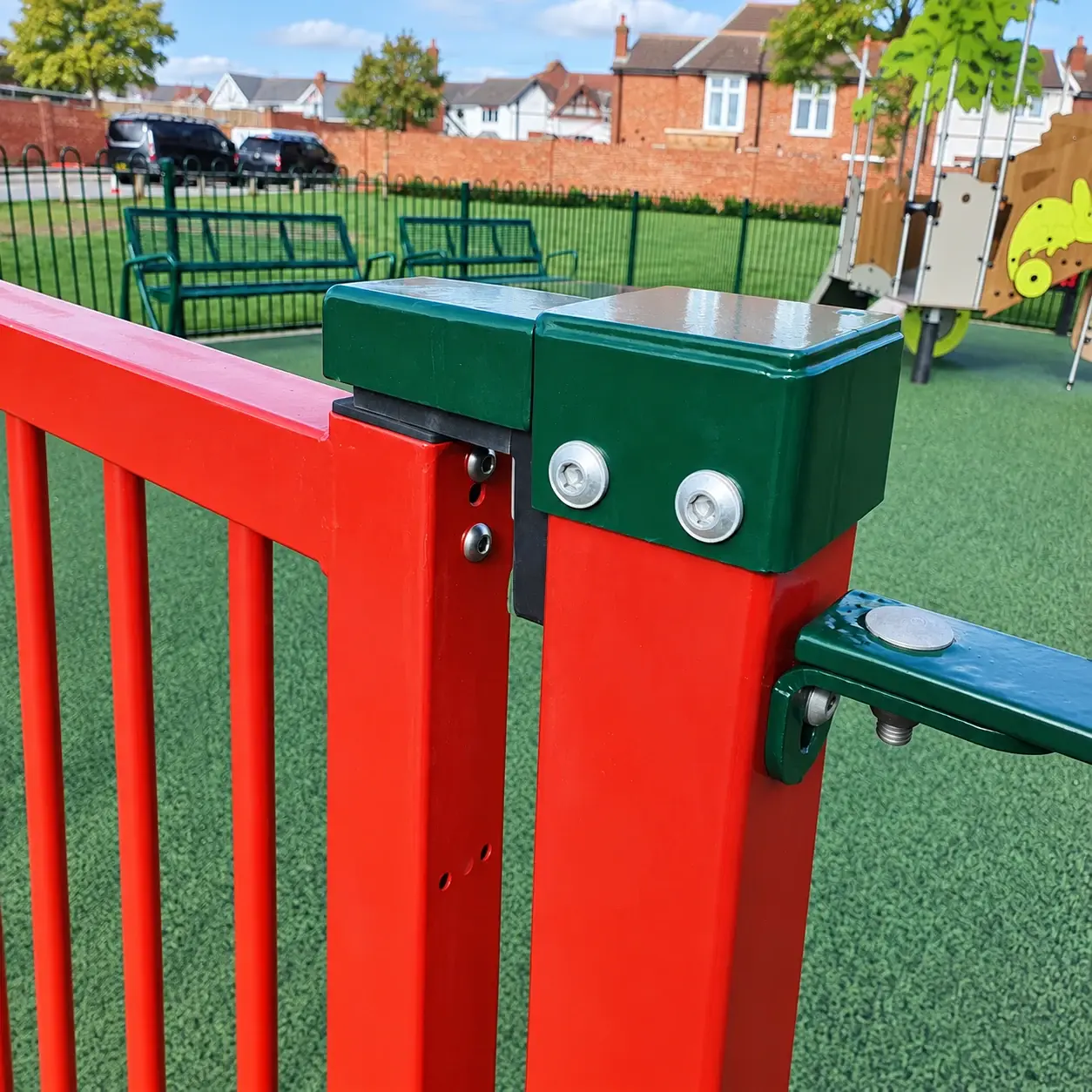 Green closer housing at the hinge side of a red playground gate