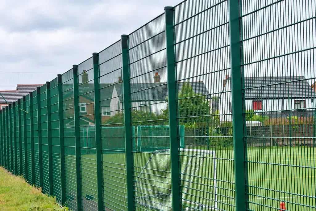 Tall green sports mesh panels beside a playing field.