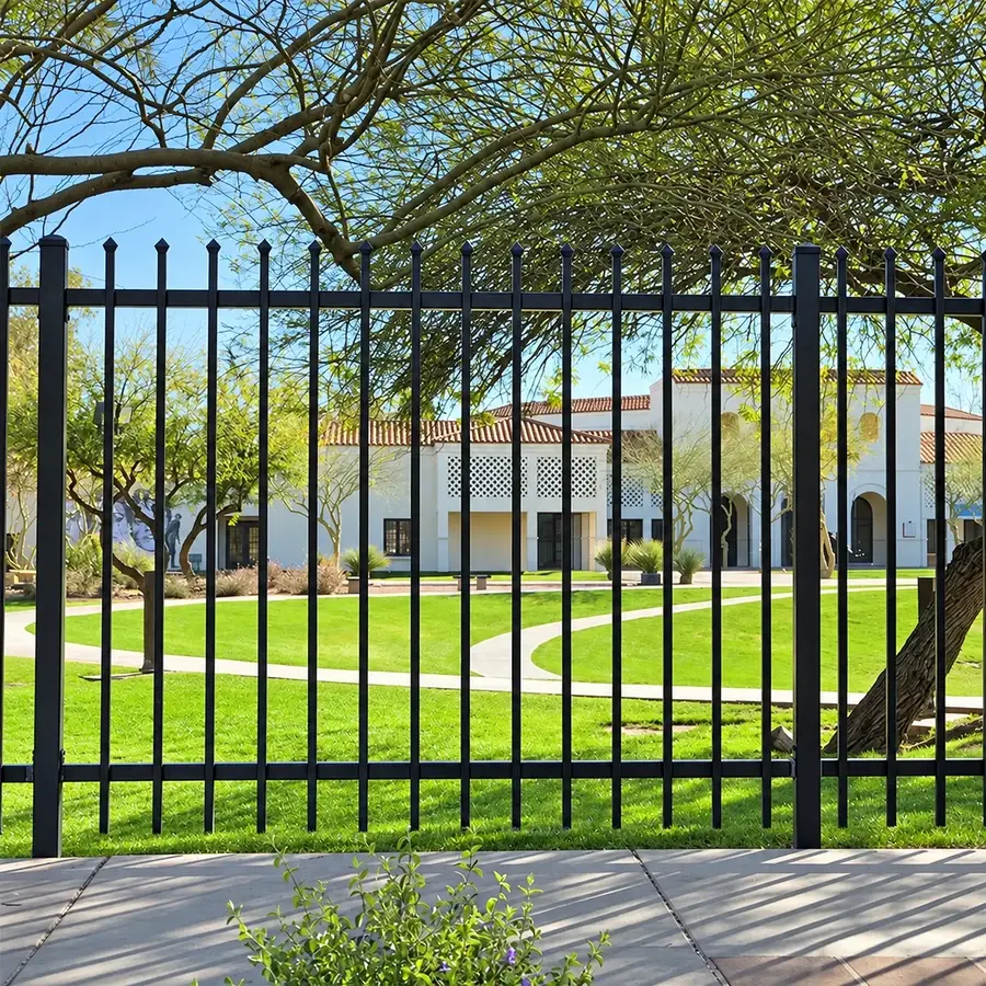 Black steel picket fence beside a lawn and trees