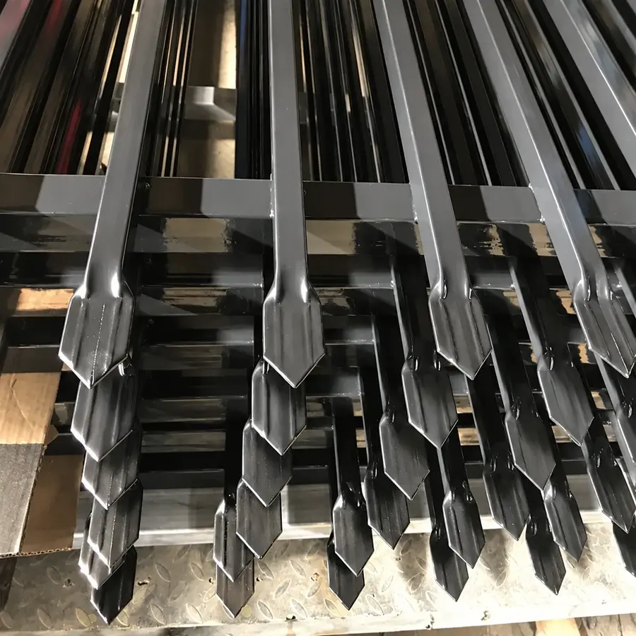 Stacked black steel panels showing formed spear tops and rails