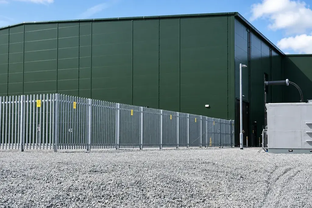 Galvanised palisade fencing around an industrial building