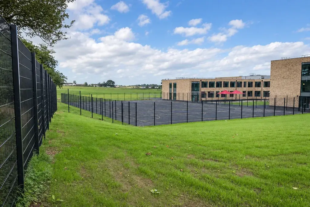 Dark mesh fencing around a grassed school boundary