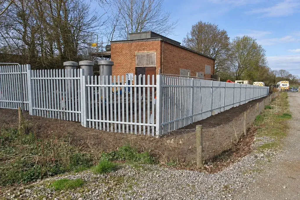 Galvanised steel palisade fencing along a sloping boundary