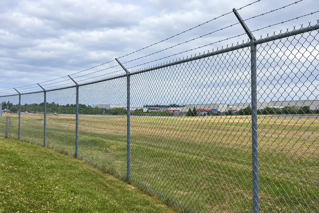 Chain-link boundary fence with angled extensions and barbed wire