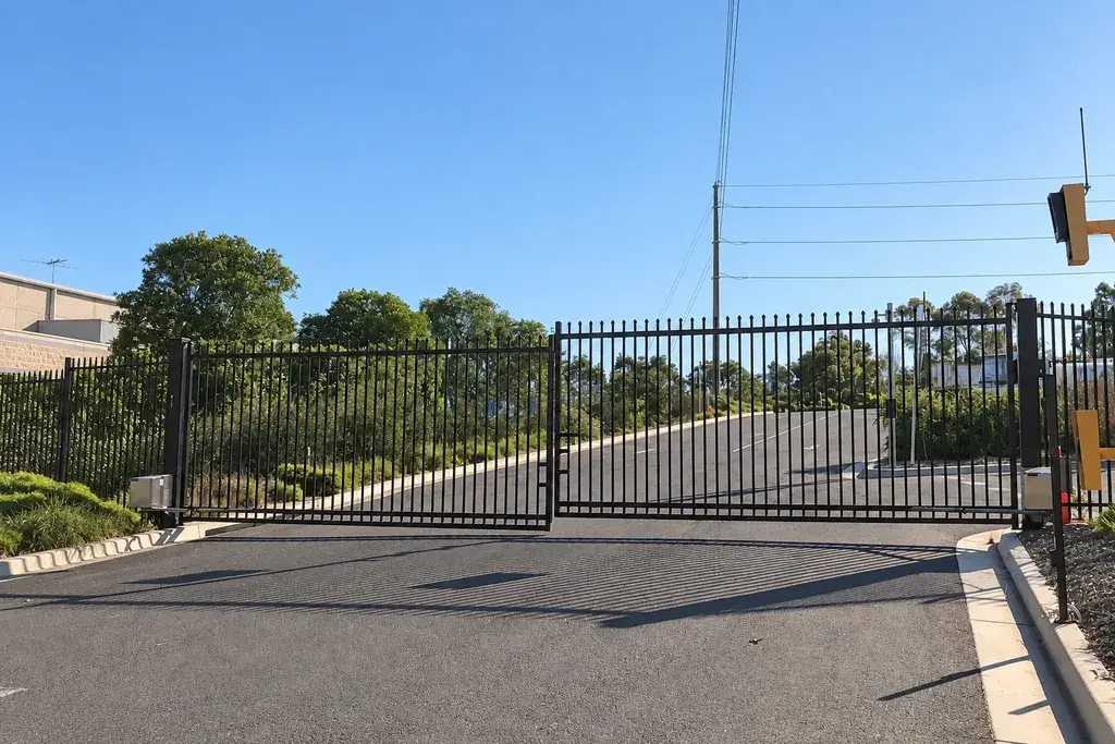 Black double-leaf steel vehicle gates across an entrance