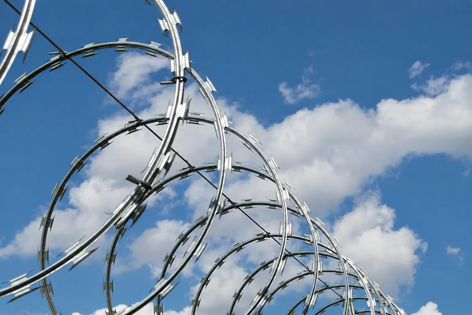 Concertina razor wire coils against a blue sky