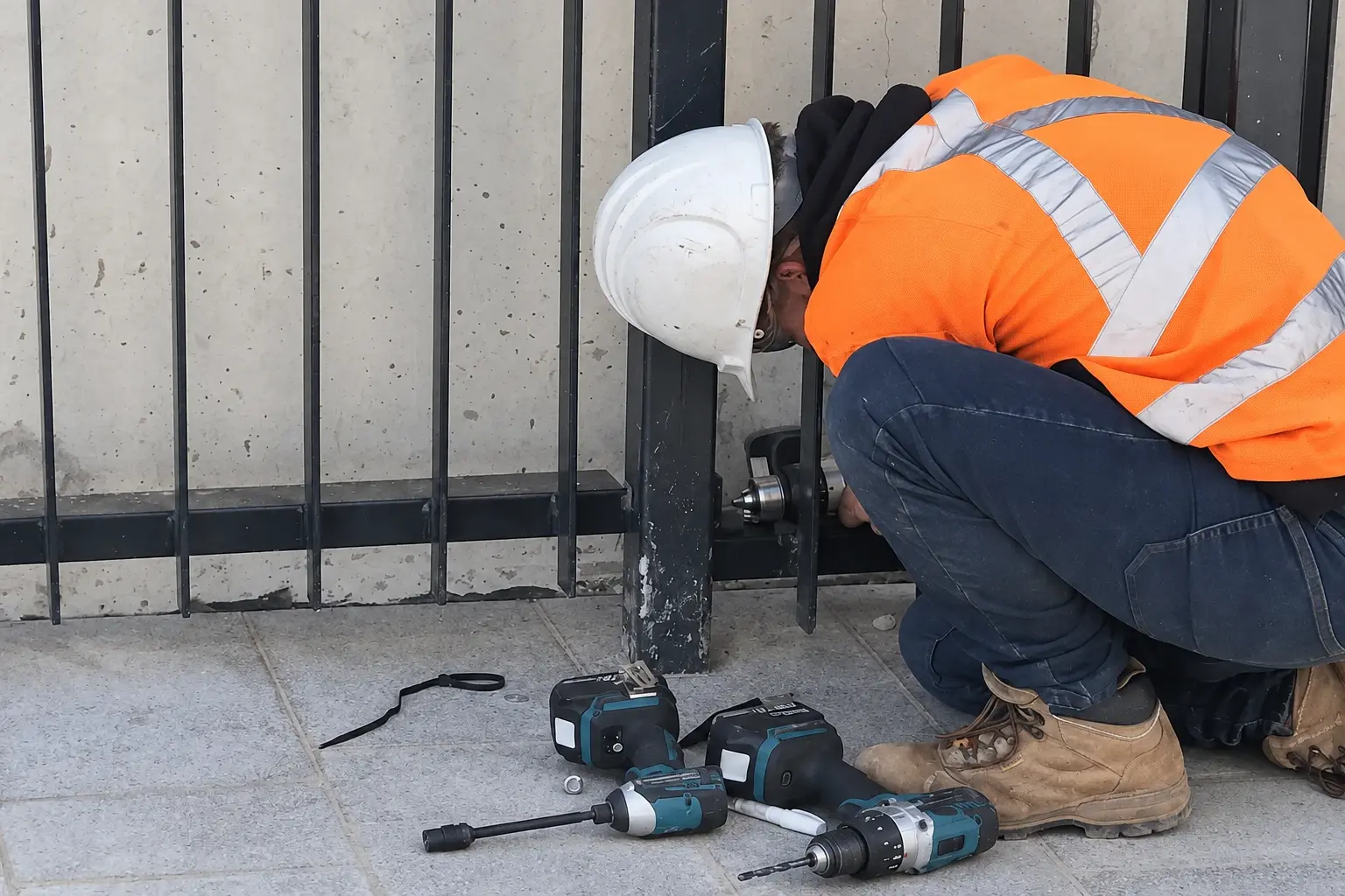 Installer fastening the base of a steel fence post