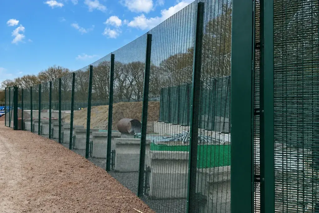 Long run of green mesh fencing around an industrial site
