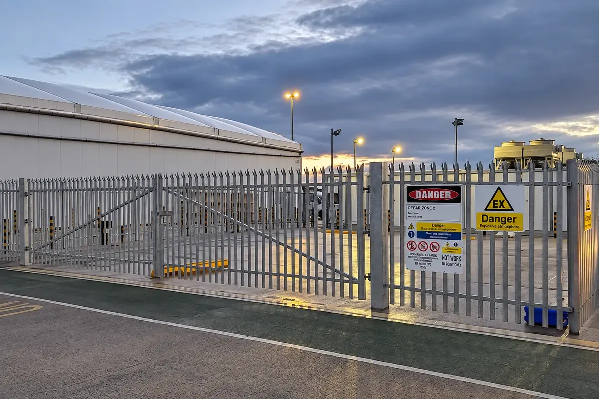 Steel security fence and vehicle gate at an industrial yard entrance