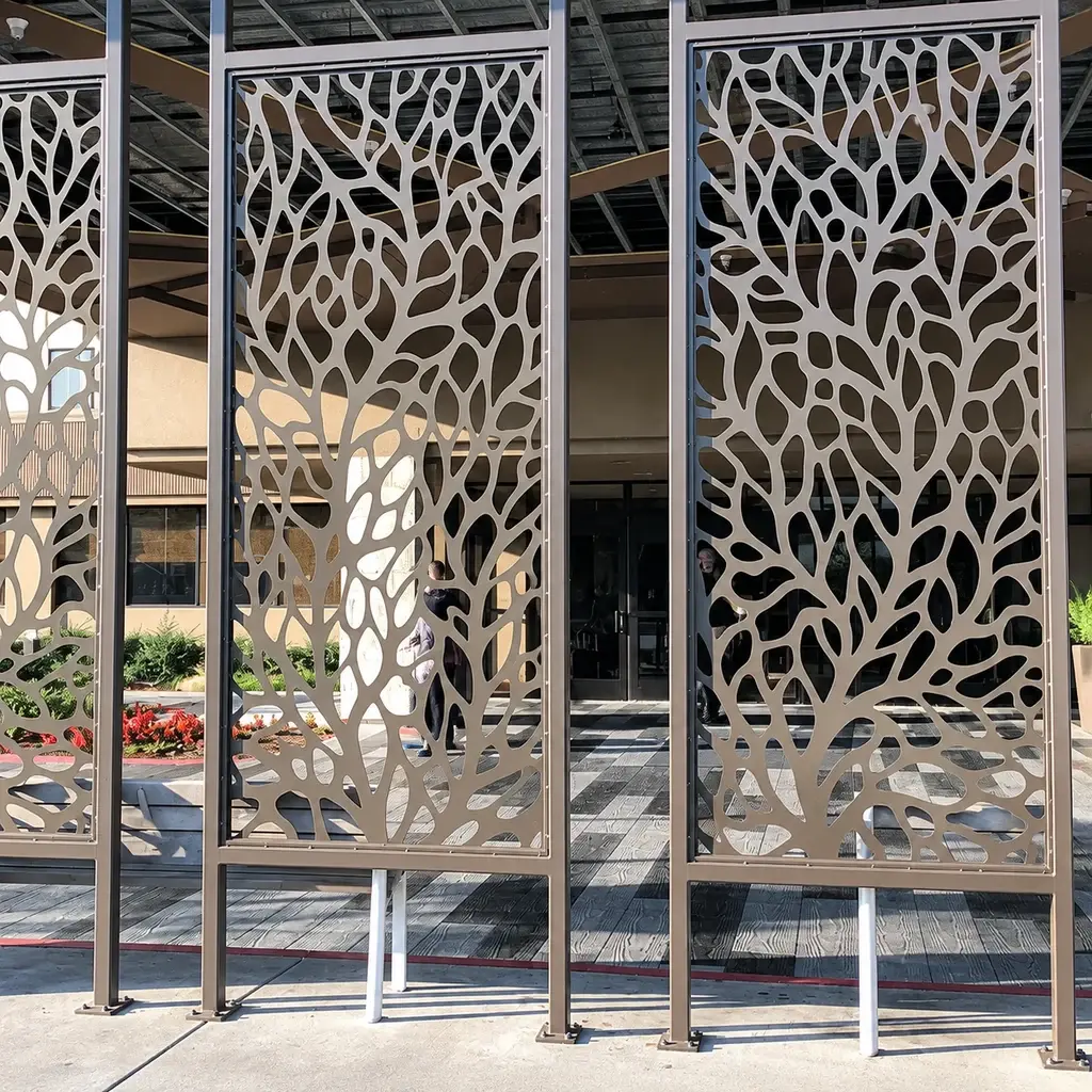 Three tree-pattern metal screen panels standing in a workshop