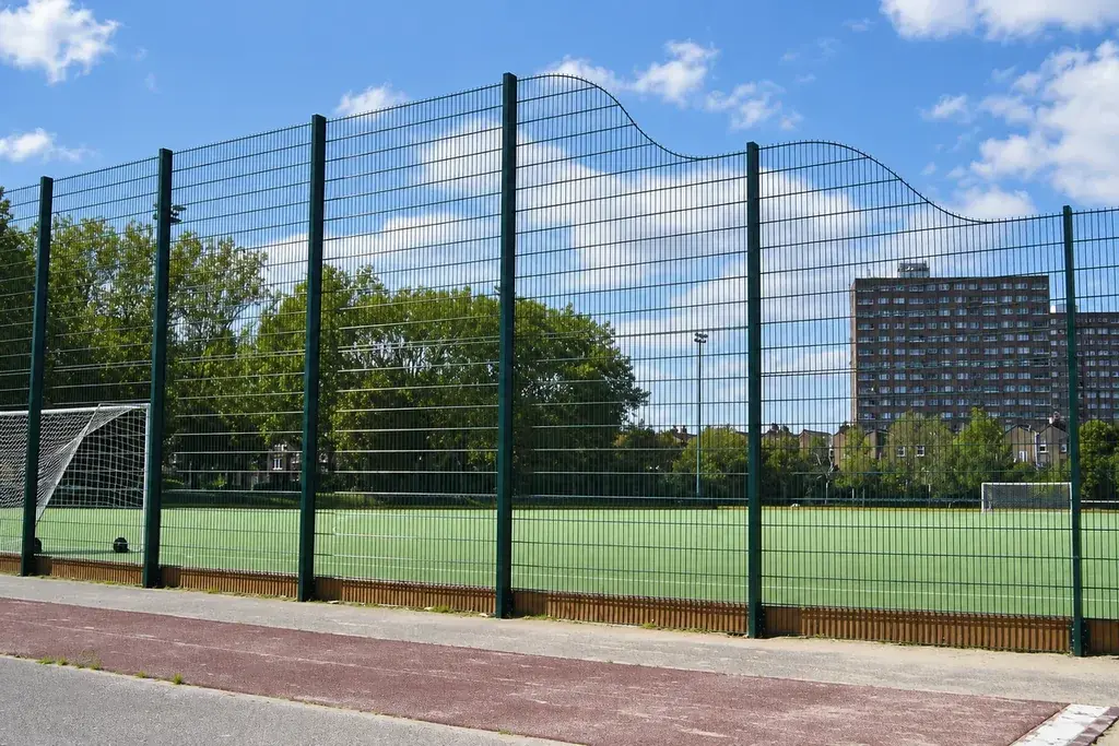 Tall black mesh fencing beside a marked outdoor sports court.