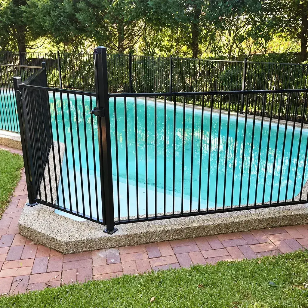 Black metal fence around a swimming pool beside paving