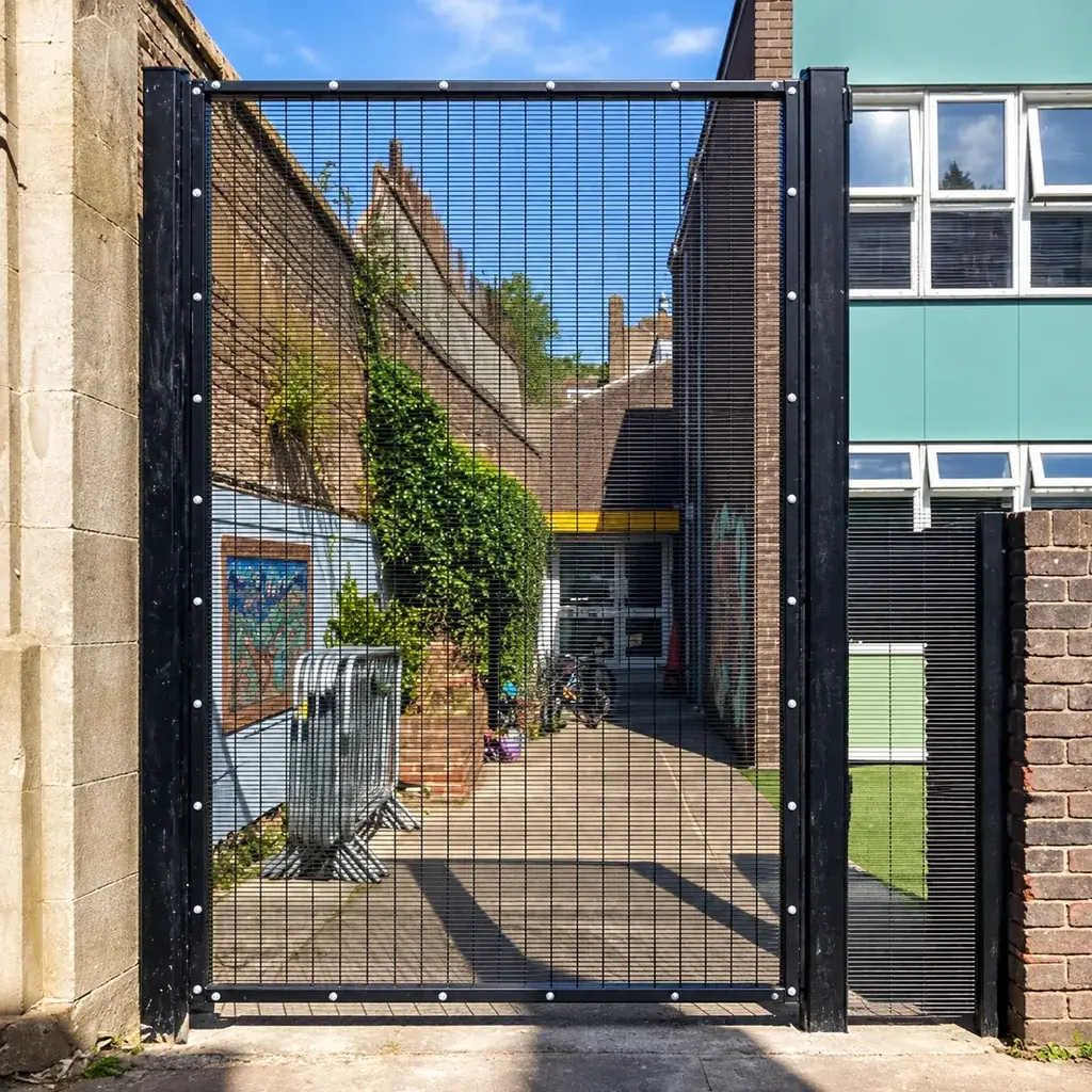 Single-leaf close-spaced mesh pedestrian gate beside a brick building