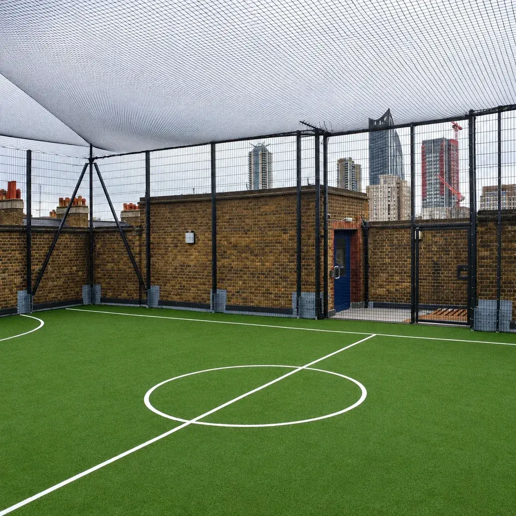 Overhead ball-retention netting above an enclosed sports court