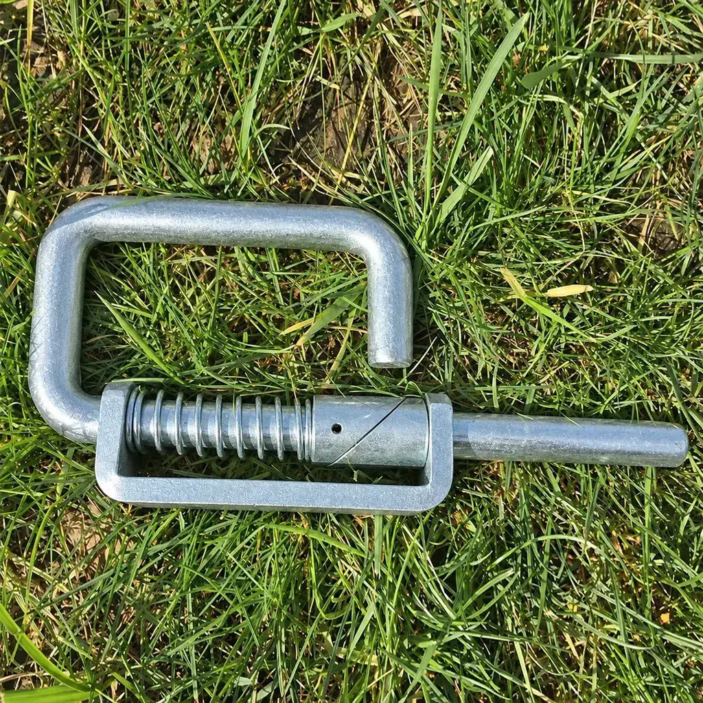 Galvanised spring-loaded gate latch lying on grass