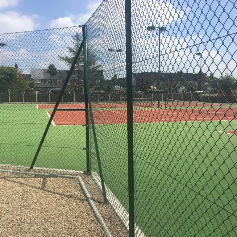Green coated chain link fence enclosing a tennis court
