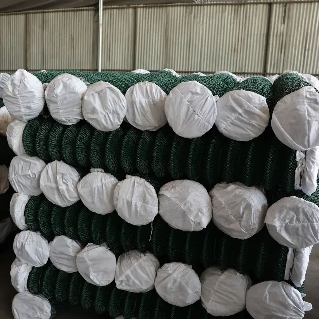 Wrapped rolls of green PVC-coated chain link mesh in storage