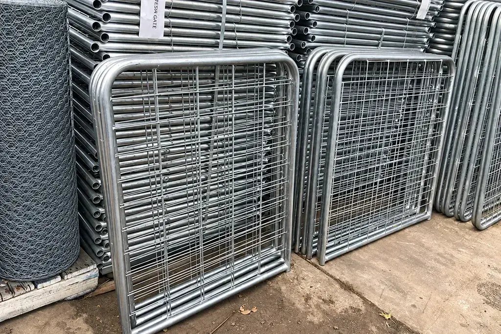 Unwrapped galvanised mesh gates standing beside stacked gate frames