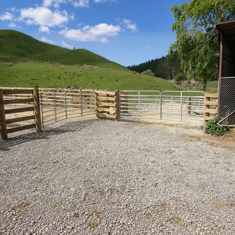 Galvanised rail farm gates across a gravel yard entrance