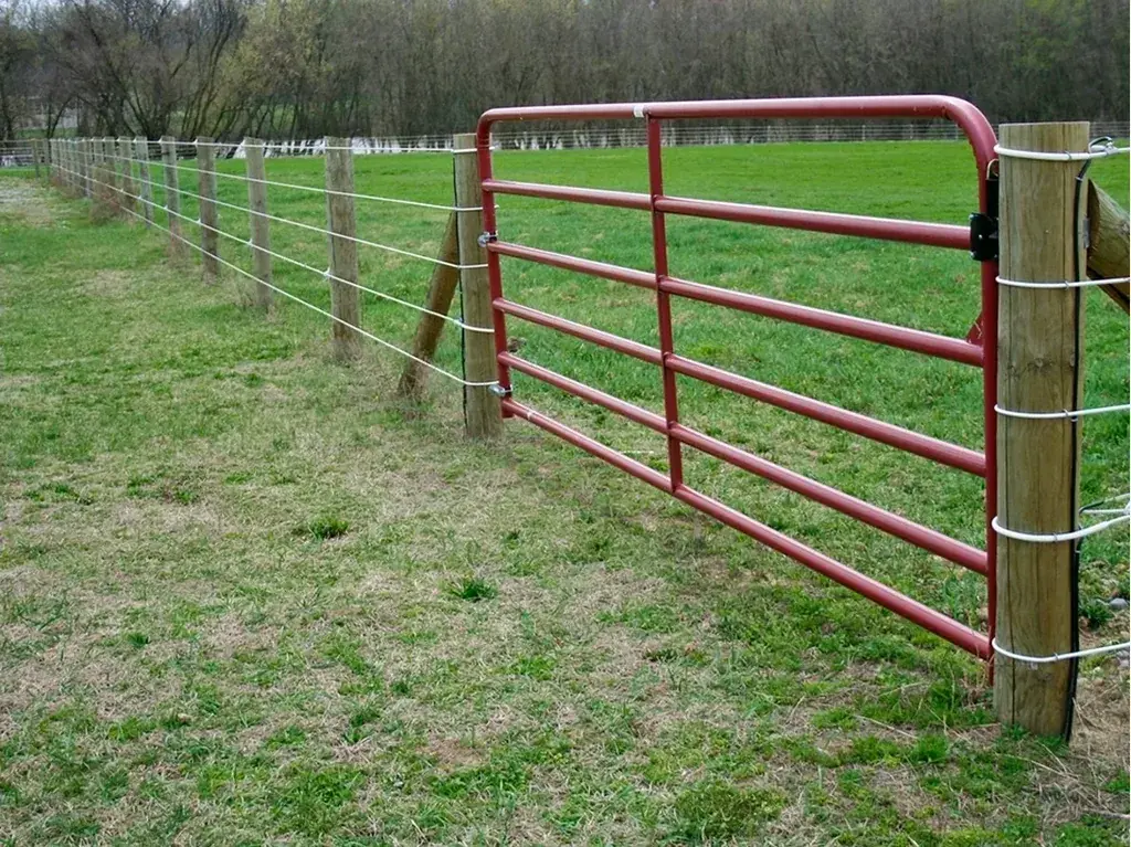 Red five-bar gate closing a farm fence opening